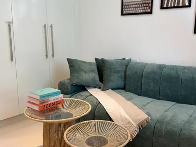 a living room with a blue couch with two tables at ASHRI HH, Bohemian Style Condo in Downtown in Dubai