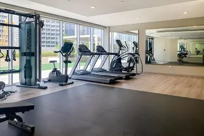 a gym with treadmills and ellipticals in a room with windows at KeyRock Living - Stylish 1BR with Pool Access in Dubai