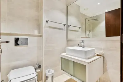 a bathroom with a sink and a toilet and a mirror at Studio APT with Pool, Gym, Squash and Badminton Courts in Dubai