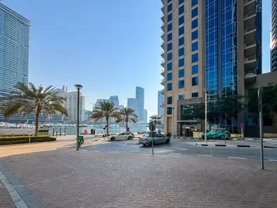 a city street with cars and palm trees and buildings at Studio APT with Pool, Gym, Squash and Badminton Courts in Dubai