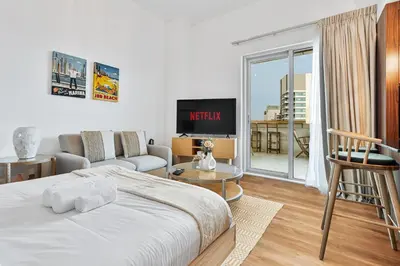 a bedroom with a bed and a couch and a tv at Studio APT with Pool, Gym, Squash and Badminton Courts in Dubai