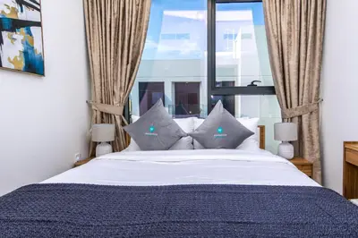 a bedroom with a bed with pillows and a window at Bloomfields Modern 2br Azizi Gardens in Dubai