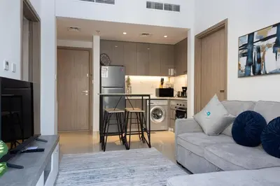 a living room with a couch and a kitchen at Bloomfields Modern 2br Azizi Gardens in Dubai