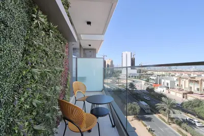 a balcony with a table and chairs and a green wall at Livbnb-Perfect 1BR Retreat in the Heart of JVC in Dubai