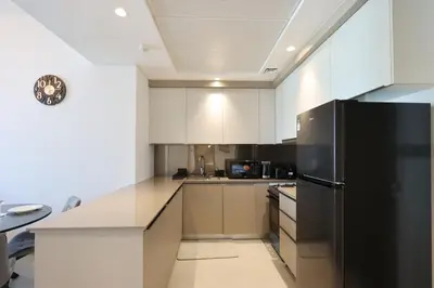 a kitchen with white cabinets and a black refrigerator at Livbnb-Perfect 1BR Retreat in the Heart of JVC in Dubai