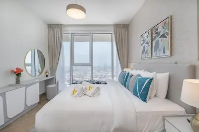 a white bedroom with a large bed with a window at Vogue Al Wasl 1 Residences Near Zabeel Park and World Trade Centre, One Bedroom Apartment with Balcony and City View, Access to all Amenities, Walkable to Max Fashion Metro Station in Dubai