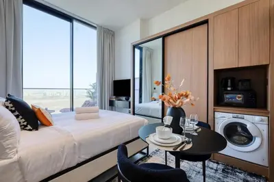 a living room with a bed and a table and a washing machine at Stunning Studio in Binghatti House in Dubai