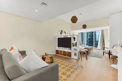 a living room with a couch and a tv at Waves - Modern Studio with Stunning Lake Views in JLT in Dubai
