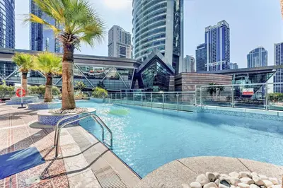 a swimming pool with a palm tree and buildings at Waves - Modern Studio with Stunning Lake Views in JLT in Dubai