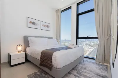 a bedroom with a bed and a large window at Escape24 Modern 1BR Balcony with City View in Dubai