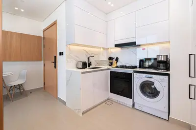 a white kitchen with a washing machine in it at Escape24 Modern 1BR Balcony with City View in Dubai