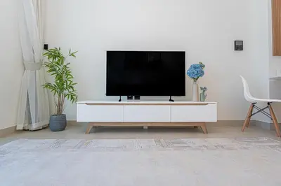 a living room with a tv on a white cabinet at Escape24 Modern 1BR Balcony with City View in Dubai