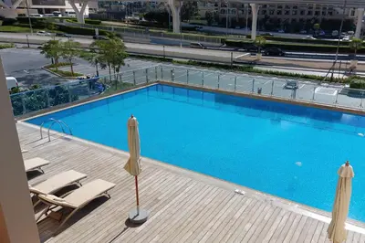 a large blue swimming pool with chairs and a building at Starfish Palm Views Studio in Dubai