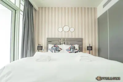 a bedroom with a white bed with two clocks on the wall at Chill 1br W Beach Views & Private Beach Access in Dubai