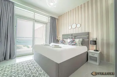 a large white bed in a room with a window at Chill 1br W Beach Views & Private Beach Access in Dubai