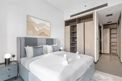 a white bedroom with a large white bed and shelves at High End 1 Bedroom with Exquisite Layout in JLT in Dubai