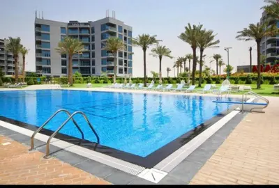 a large swimming pool with chairs and palm trees at 012 - Dubai South in Dubai