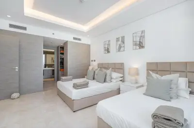 a white bedroom with two beds and a couch at Luxury Apt with Full Burj Khalifa Skyline Views in Dubai