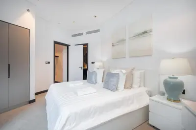 a white bedroom with a white bed and a lamp at Water Front Apartment, Burj Khalifa Views in Dubai