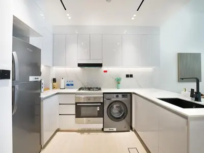 a white kitchen with a washing machine in it at EasyGo- Stylish 1BDR with view and astonishing Facilities JVC in Dubai