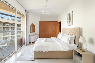 a bedroom with a large bed and a balcony at Luxury 1BR with Lake View Near Downtown Balcony and Pool Access in Dubai