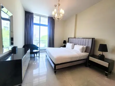 a bedroom with a bed and a desk and a chandelier at Polo Residence C1 - Blue Ocean Holiday Homes in Dubai