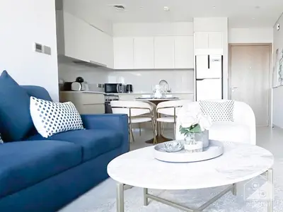 a living room with a blue couch and a table at Luxurious Burj Royale 1B Apt With Balcony & City Views in Dubai