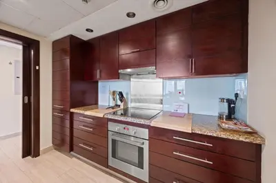 a kitchen with wooden cabinets and a stove top oven at Burj Khalifa View Apartment with Balcony Downtown Dubai in Dubai