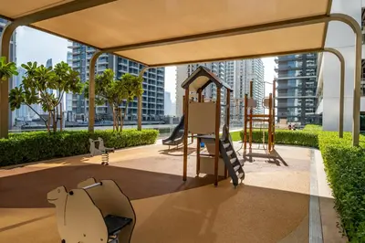 a playground with a slide and chairs in a building at Homes & Beyond I Pristine 2BR with Waterfront view in Dubai