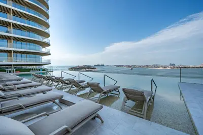 a row of chaise lounge chairs on a balcony with the ocean at Homes Beyond I Stunning Oceanfront 2 BR Apartment in Dubai