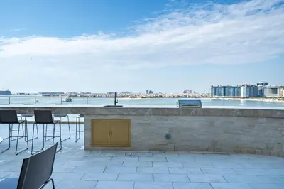 a patio with chairs and a bar with a view at Homes Beyond I Stunning Oceanfront 2 BR Apartment in Dubai