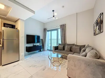 a living room with a couch and a refrigerator at Family friendly 2-bedroom in Dubai