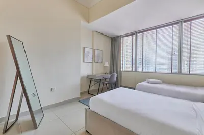 a bedroom with two beds and a desk and a window at Cozy 2bd in Dubai Marina in Dubai
