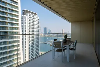 a balcony with a table and chairs and a view of the city at Homes Beyond I Modern 2BR Getaway with Beach Access in Dubai