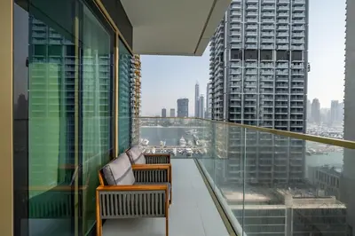 a balcony with two chairs and a view of a city at Homes Beyond l Relaxing 1BR Oasis with Beach Access in Dubai