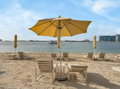 a yellow umbrella and chairs on a beach at Homes Beyond I 1BR Coastal Haven Walk to the Beach in Dubai