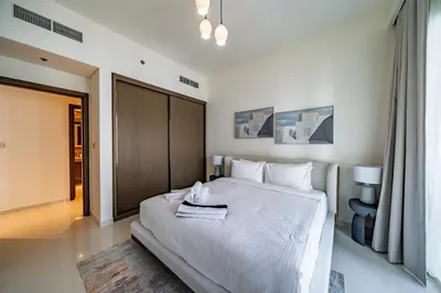 a bedroom with a white bed with a towel on it at Homes Beyond I 1BR Coastal Haven Walk to the Beach in Dubai