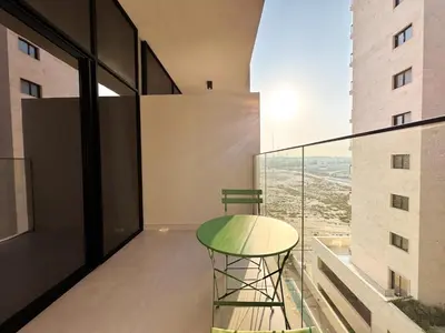 a table and a chair on a balcony with a view at Stylish Studio in the Heart of Al Furjan 20AB4 in Dubai