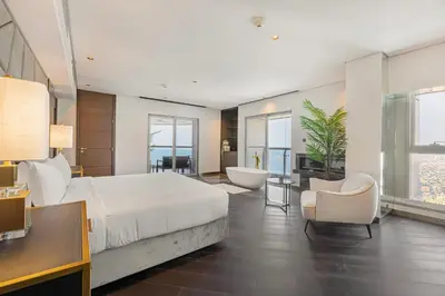 a bedroom with a large bed and a tub and a chair at Daniels 3BR at Princess Tower With Full Palm Jumeirah View in Dubai