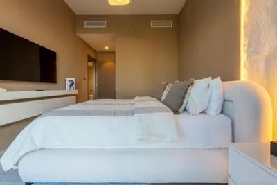 a bedroom with a white bed and a tv at Stunning Burj Khalifa & Fountain Views - Luxury 2BR - 5 minutes walk to Dubai Mall in Dubai