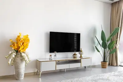 a living room with a tv on a white wall at Modern 1Br in the Heart of Dubai by SIMPLY COMFORT in Dubai