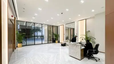 a man sitting at a desk in a lobby at Brand New Apt On Top Floor 1BR w Spa And Pool in Dubai