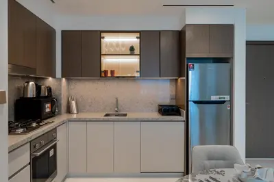 a kitchen with white cabinets and a blue refrigerator at Homes Beyond I Seaside 1BR Retreat with Beach Access in Dubai
