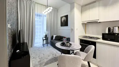 a kitchen and living room with a table and a couch at Exclusive Lakeview Haven - Zada Tower by Keyrock Living in Dubai