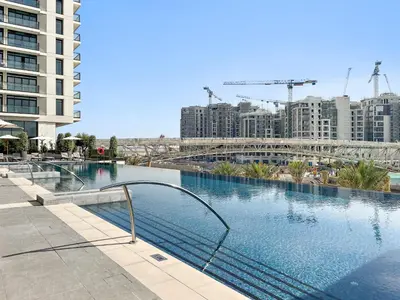 a large swimming pool in a city with tall buildings at 1BR Palace Residences, City View in Dubai