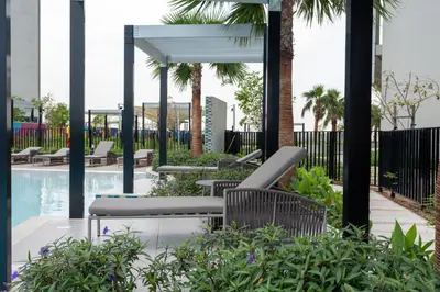 a patio with chairs and a swimming pool with palm trees at Keyrock Living - Exclusive Luxury at Aykon Tower in Dubai