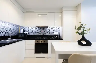 a kitchen with white cabinets and a table with a plant at Keyrock Aykon Tower, Business Bay - Pool & Gym in Dubai