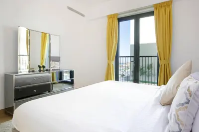 a bedroom with a white bed and a balcony at 015 - Le Pont 1 in Dubai