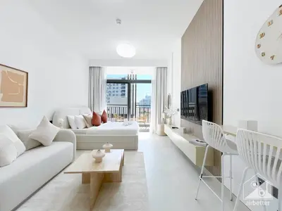 a white living room with a couch and a table at Studio Charm at Legacy Ideal Arjan Stay in Dubai