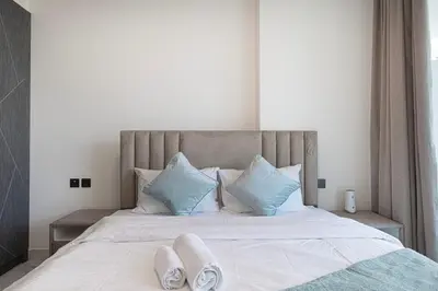 a bedroom with a large white bed with blue pillows at NEW 2BR in Arjan with Private Pool in Dubai